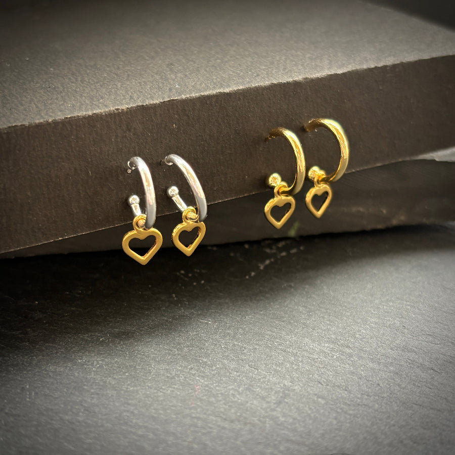 Set of gold and silver heart-shaped earrings on a dark surface