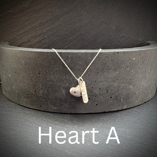 Silver necklace with heart pendant on a dark surface