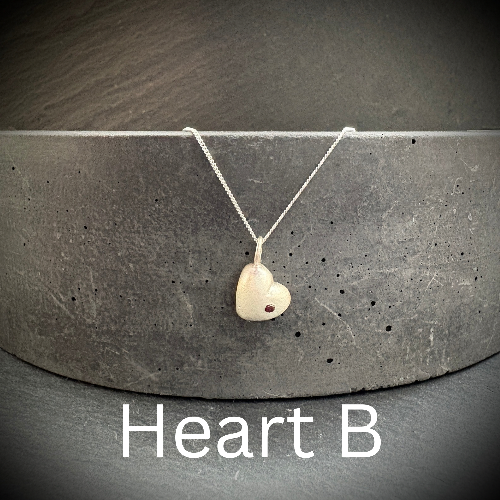Heart-shaped pendant necklace on a gray concrete surface with 'Heart B' text.