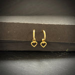 Gold heart-shaped hoop earrings on a dark surface