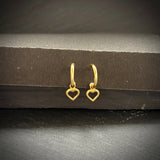 Gold heart-shaped hoop earrings on a dark surface