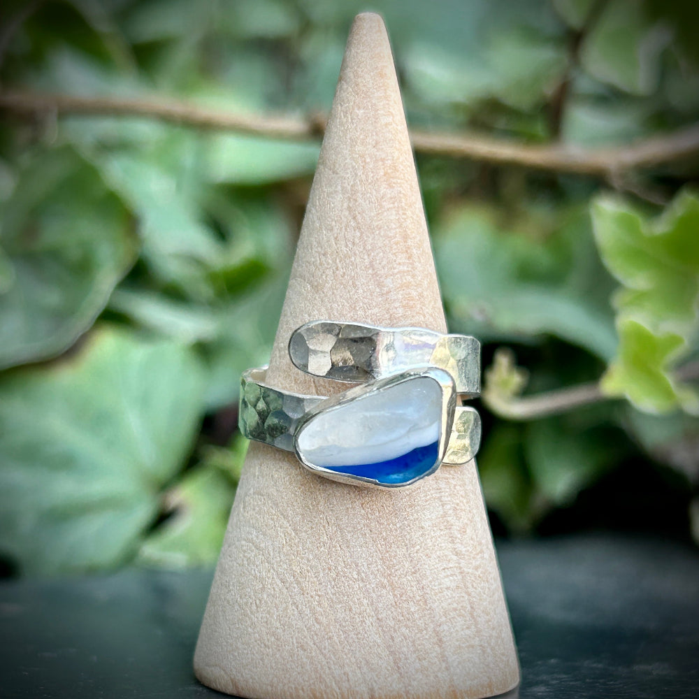 Silver ring with a blue Seaham Sea Glass on a cone-shaped display stand against a green leafy background