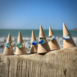 Seaham Sea glass Sterling Silver adjustable Rings on cone-shaped stands against a beach background