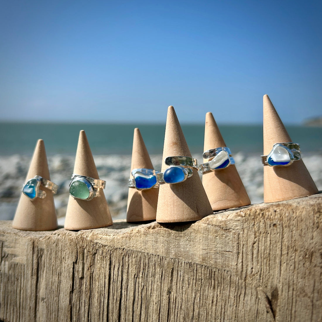 Seaham Sea glass Sterling Silver adjustable Rings on cone-shaped stands against a beach background