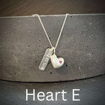 Necklace with solid silver heart-shaped pendant and engraved love tag on a dark surface