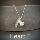 Necklace with solid silver heart-shaped pendant and engraved love tag on a dark surface
